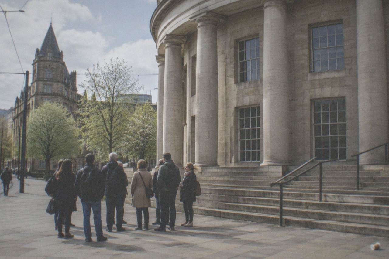 A walking tour group gathered on a Manchester street beside the Central Library