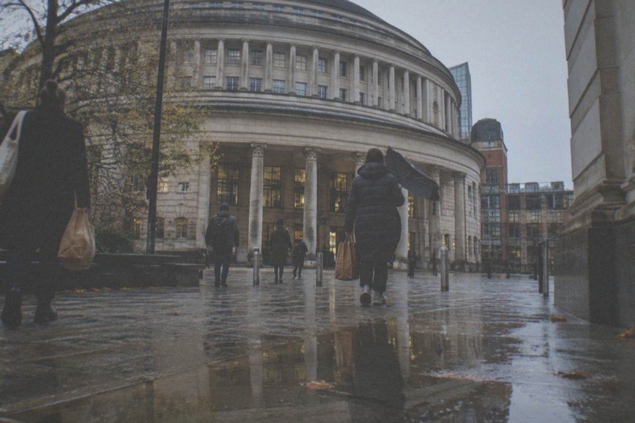 Shoppers crossing St Peter's Square in central Manchester with the Central Library building behind them